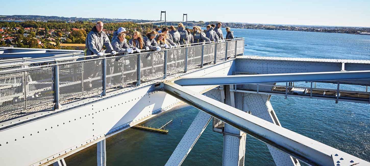 En flok mennesker på bridgewalking på den gamle Lillebæltsbro. Den nye Lillebæltsbro anes i baggrunden.