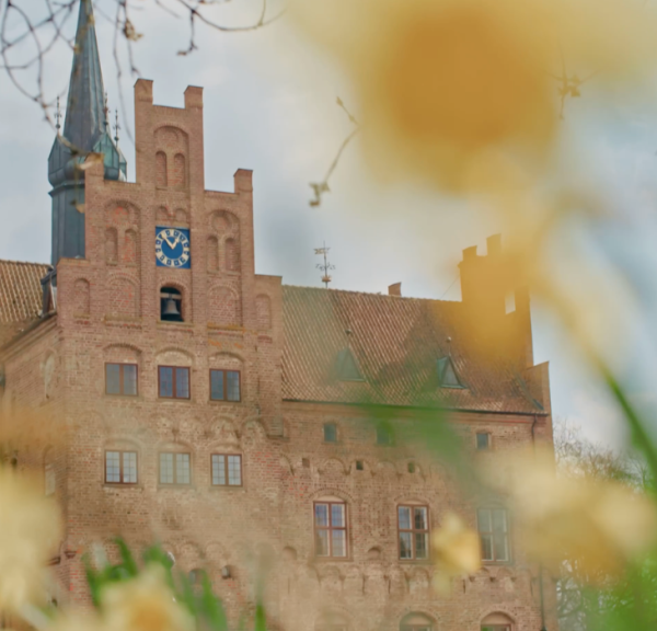 Egeskovs facade med påskeliljer i forgrunden