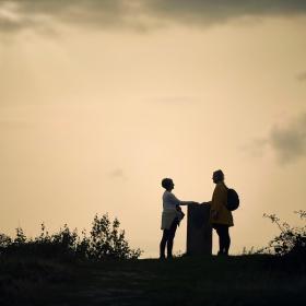 To personers silhouetter på toppen af en bakke 