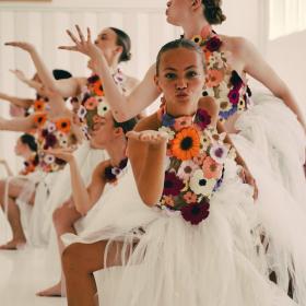 En opvisning af unge kvindelige balletdansere iført hvide klæder og friske blomster